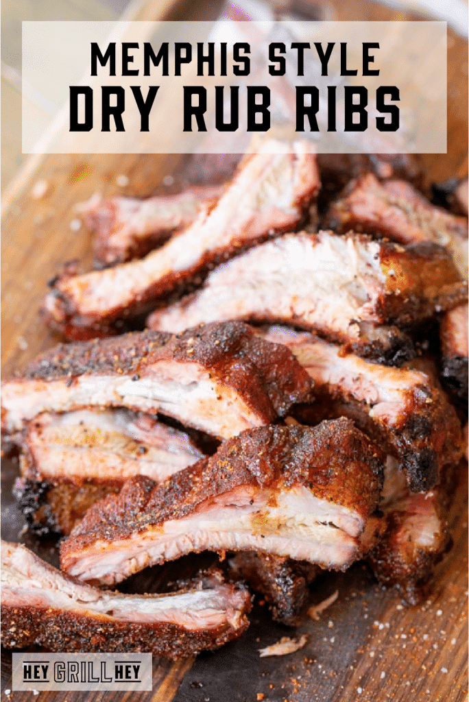 Sliced Memphis style dry rub ribs arranged in a pile on a wood cutting board with text overlay - Memphis Style Dry Rub Ribs.
