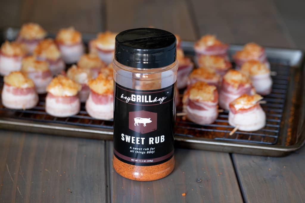 Tray full of filled bacon cream cheese next to a bottle of Sweet Rub. 