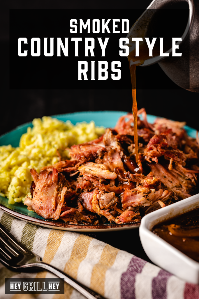 Smoked country style ribs shredded and on a dinner plate next to potatoes with text overlay - Smoked Country Style Ribs.
