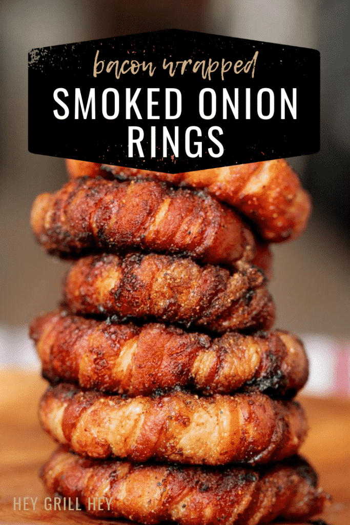 A stack of onion rings wrapped in bacon on a wooden cutting board