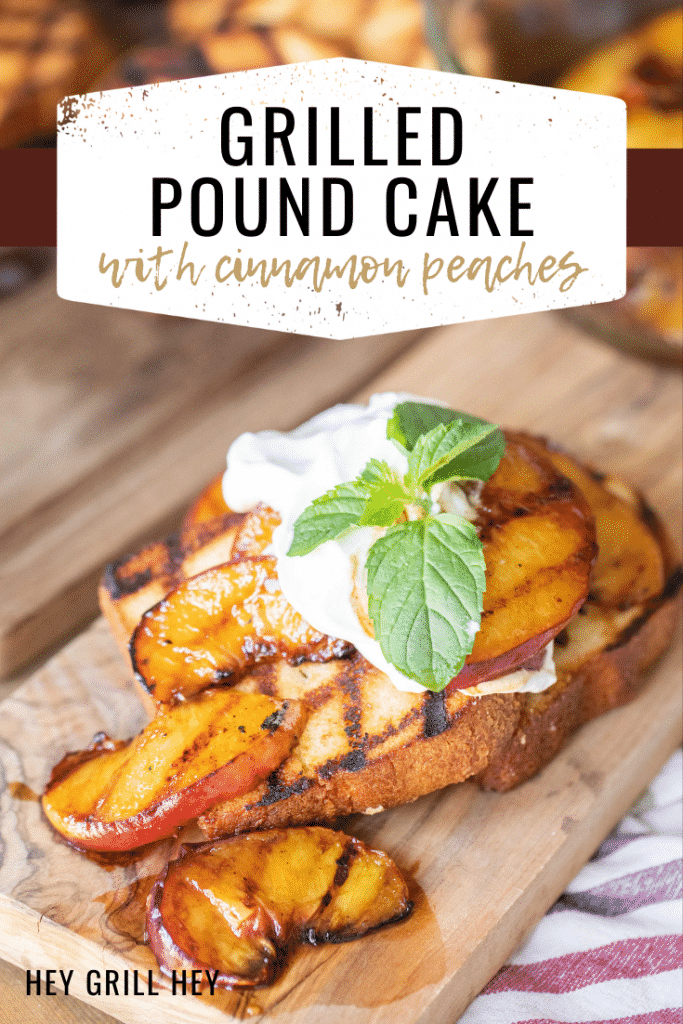 Grilled pound cake topped with grilled peaches, whipped cream, and mint leaves on a wooden cutting board. Text overlay: Grilled Pound Cake with Cinnamon Peaches.