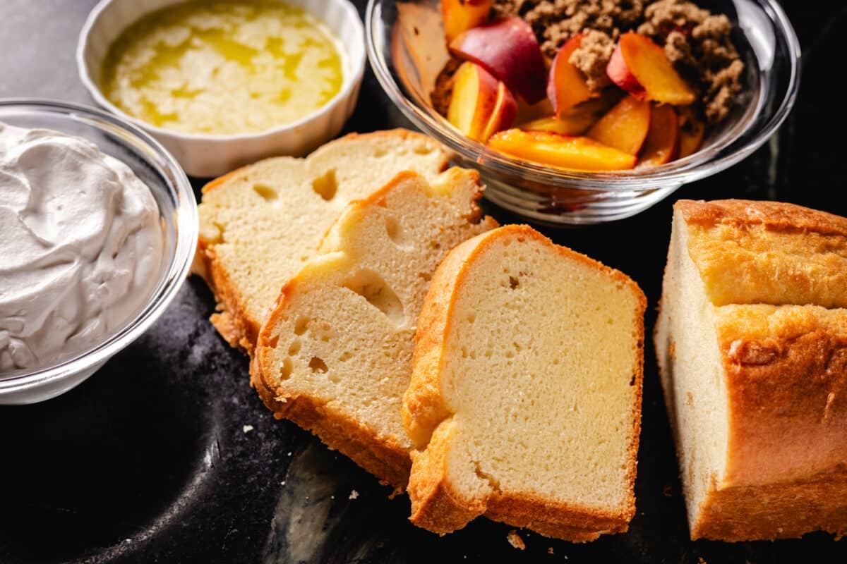 Cake slices next to bowls of cream, peaches, and butter.