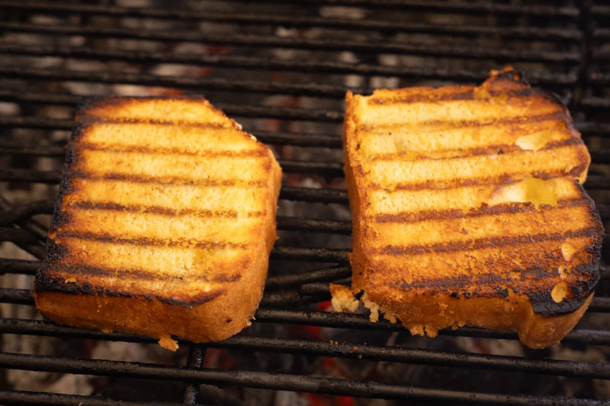 Two slices of yellow cake on the grates of a grill.
