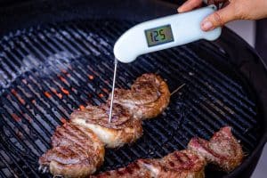 Instant-read thermometer taking the temperature of grilled picanha at 125 degrees F.