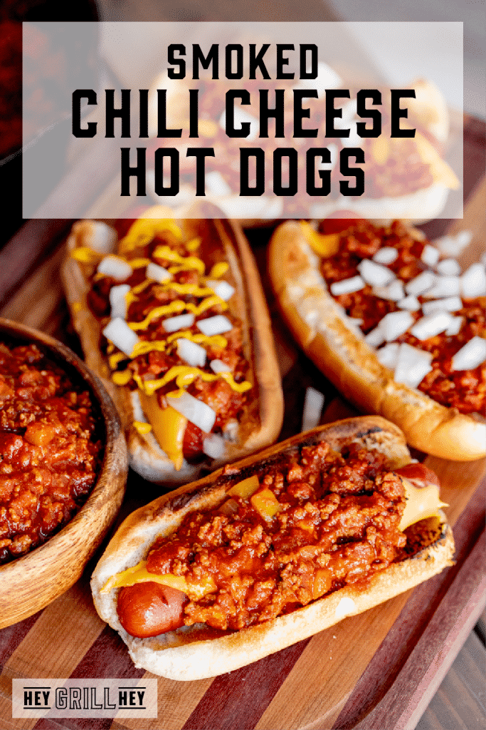 Chili cheese hot dogs on a wooden cutting board. Text overlay reads: Smoked Chili Cheese Hot Dogs.