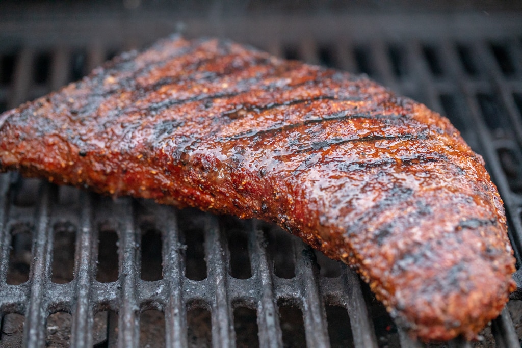 smoked coffee rub tri tip on the grill grates of a smoker.