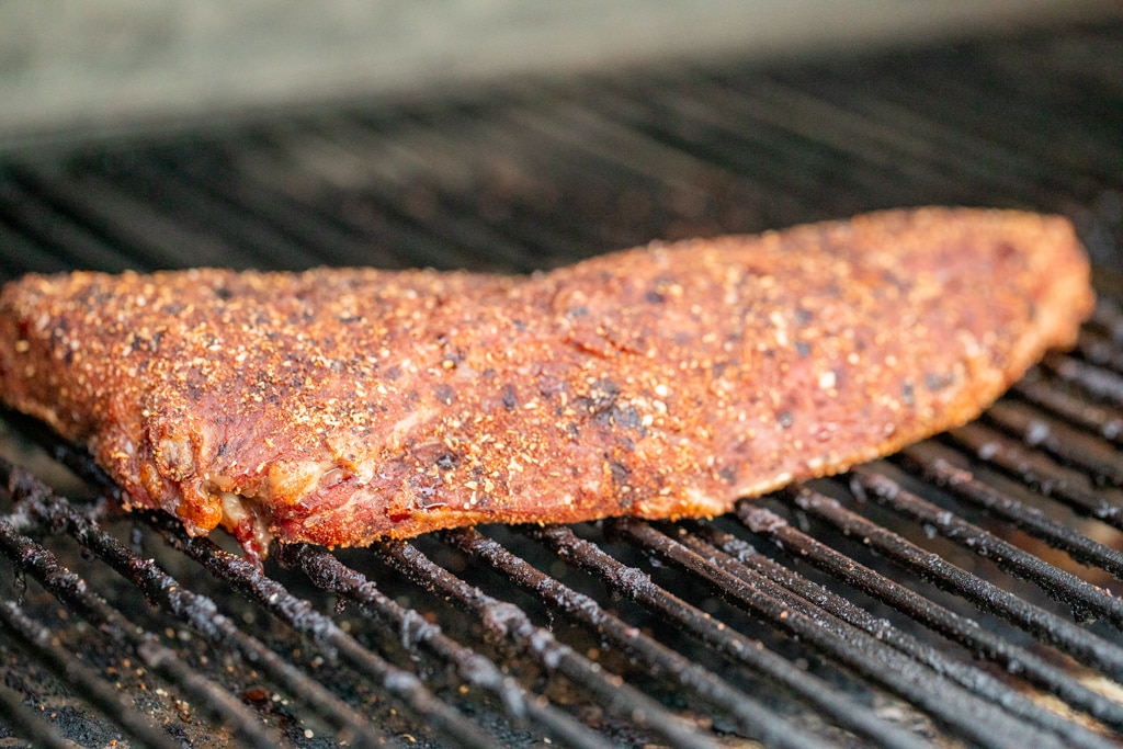 coffee rub tri tip on the grill grates of a smoker.