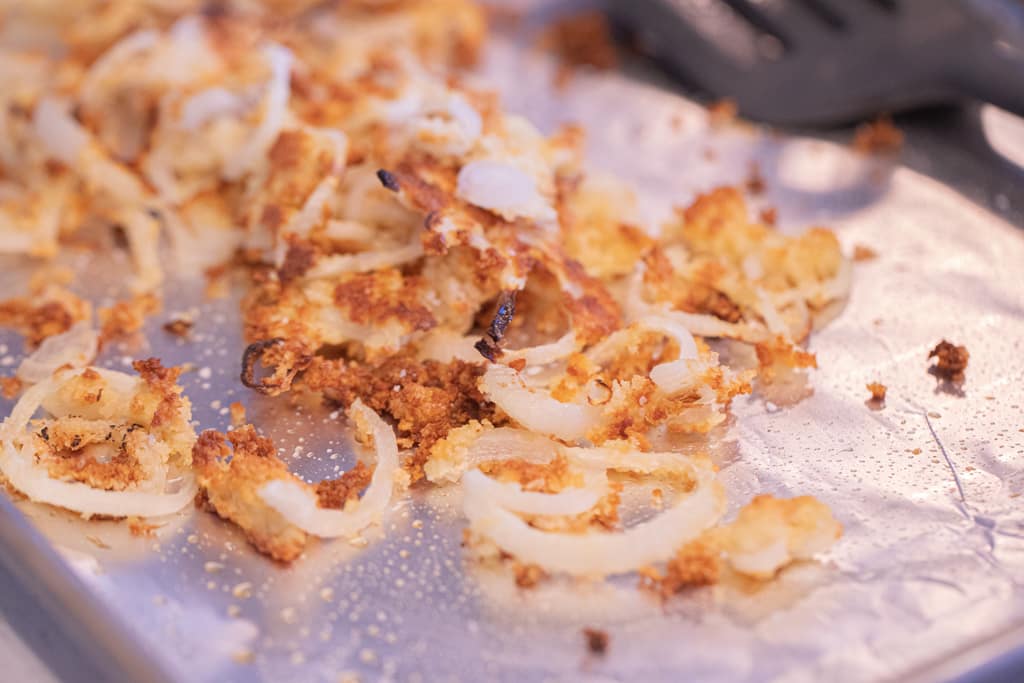 Fried onions stacked on aluminum foil.