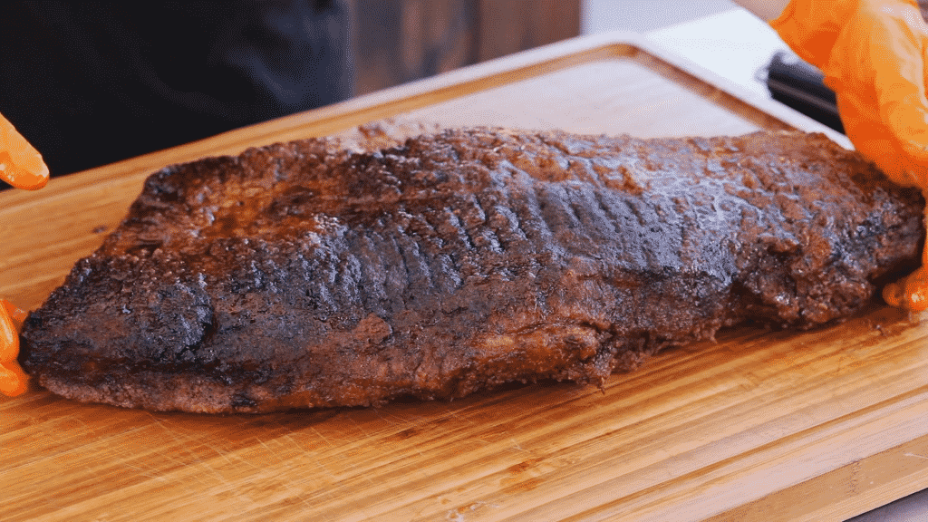Hot and fast smoked beef brisket on a wooden cutting board.