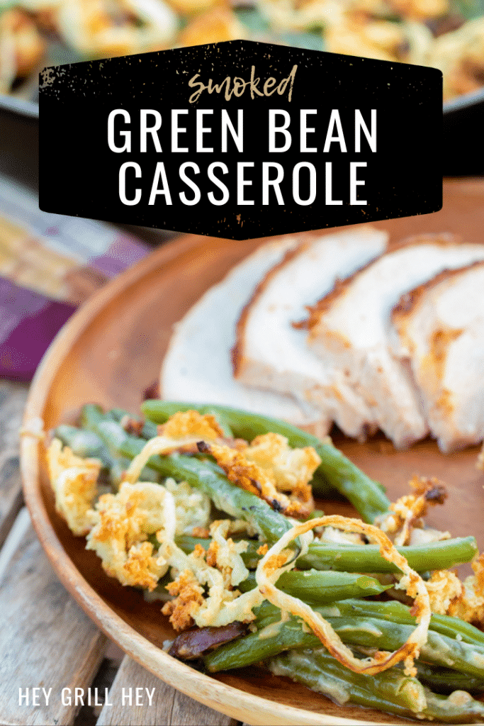 Green bean casserole on a plate next to sliced meat. Text overlay reads, "Smoked Green Bean Casserole."