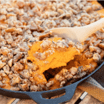 Wooden spoon taking a scoop out of a sweet potato casserole.