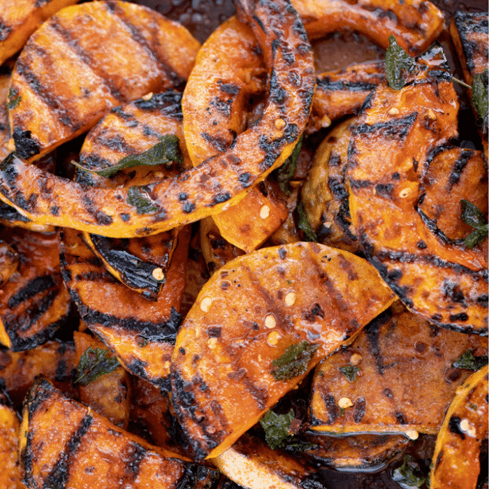 Grilled butternut squash slices stacked on a plate.