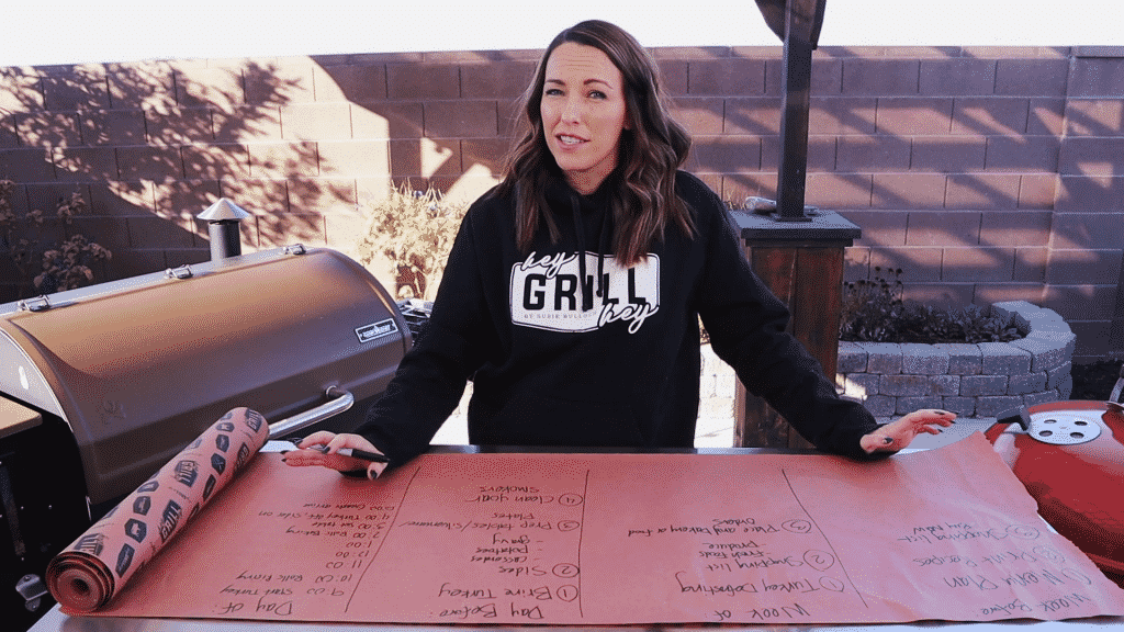 Susie stands in front of a large piece of butcher paper with a Thanksgiving meal plan written on it.