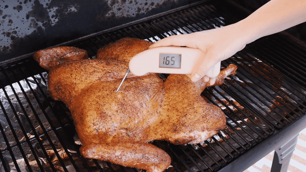 Instant read thermometer taking a temperature of 165 degrees F in a smoked spatchcock turkey.