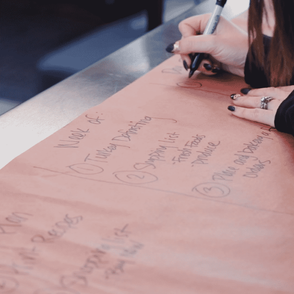 Susie writes a list of items to complete the week of Thanksgiving on peach butcher paper.