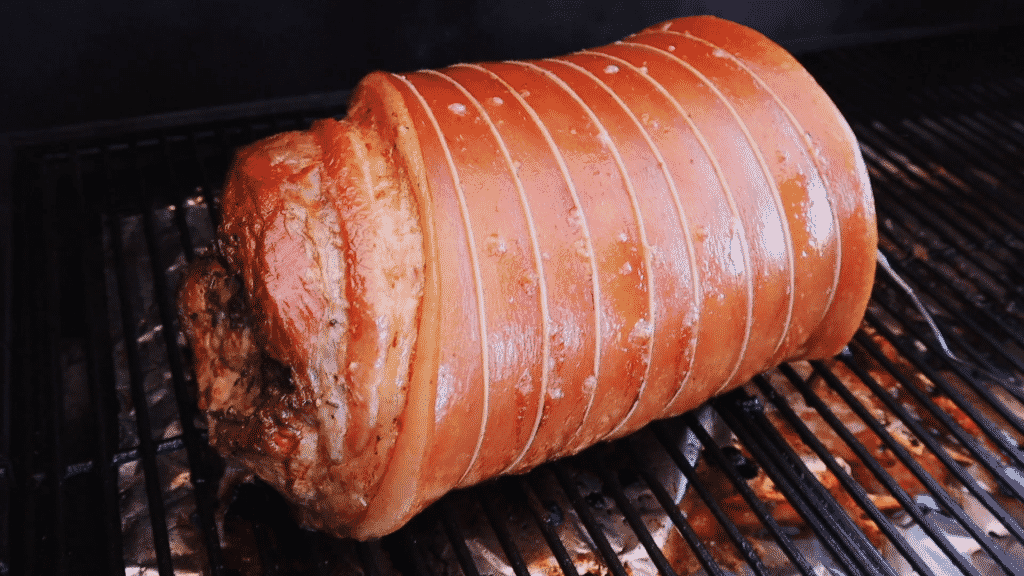 Smoked porchetta on the grill grates of a smoker.