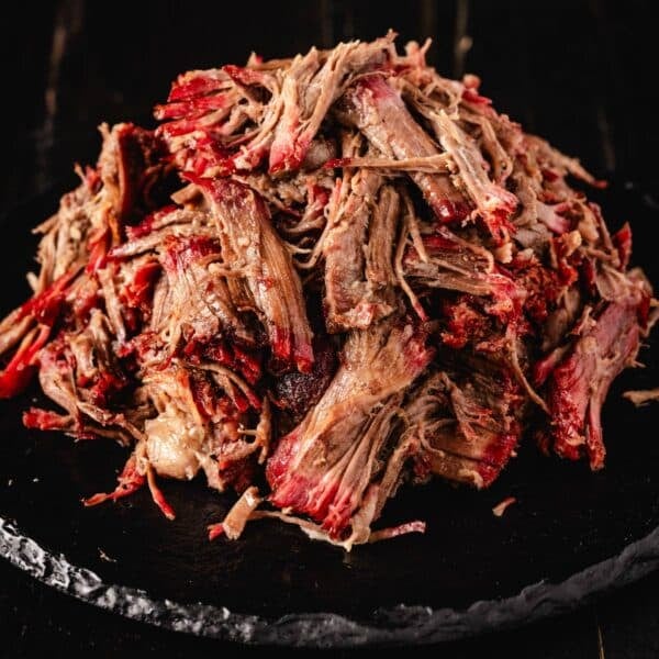 Pulled beef piled on black serving platter.