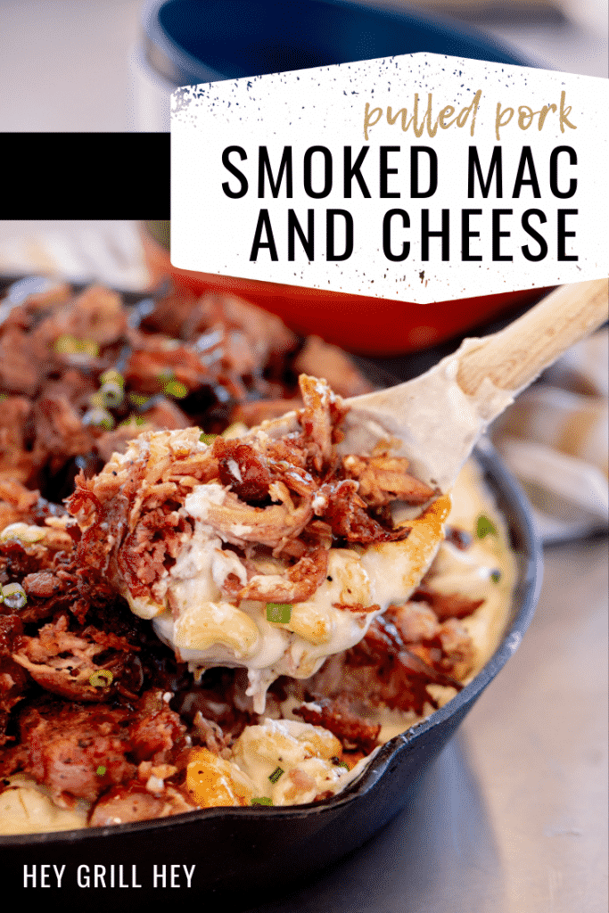 Smoked pulled pork mac and cheese being pulled out of a cast iron skillet with a wooden spoon. Text overlay reads: Pulled Pork Smoked Mac and Cheese.