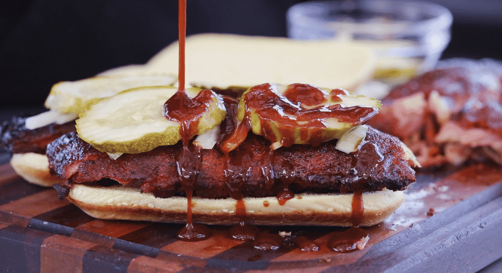 Everything BBQ Sauce being drizzled on a smoked rib sandwich.
