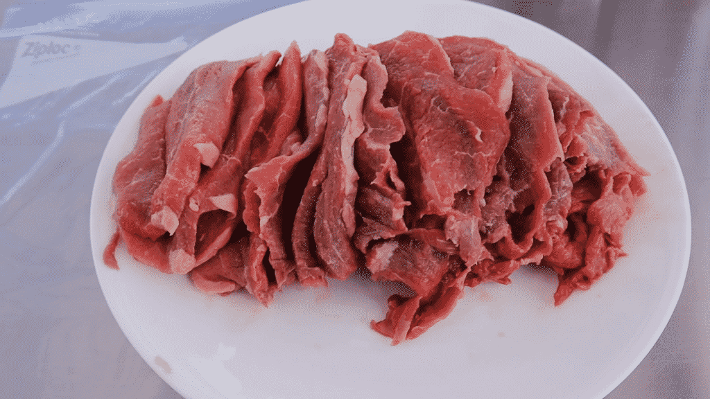 Sliced uncooked rump roast on a white plate.