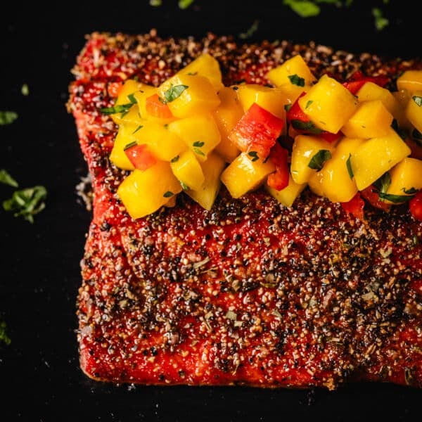 A closeup shot of grilled salmon topped with mango salsa.