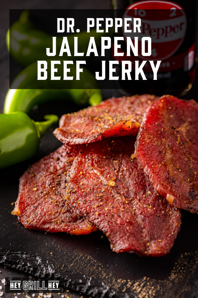 Dr. Pepper Jalapeno beef jerky in a pile next to whole jalapenos with text overlay - Dr. Pepper Jalapeno Beef Jerky.