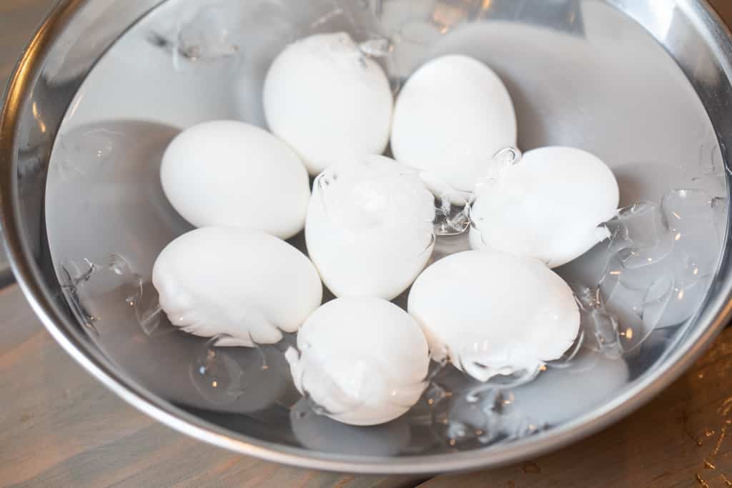 Eight eggs in a metal bowl full of water.
