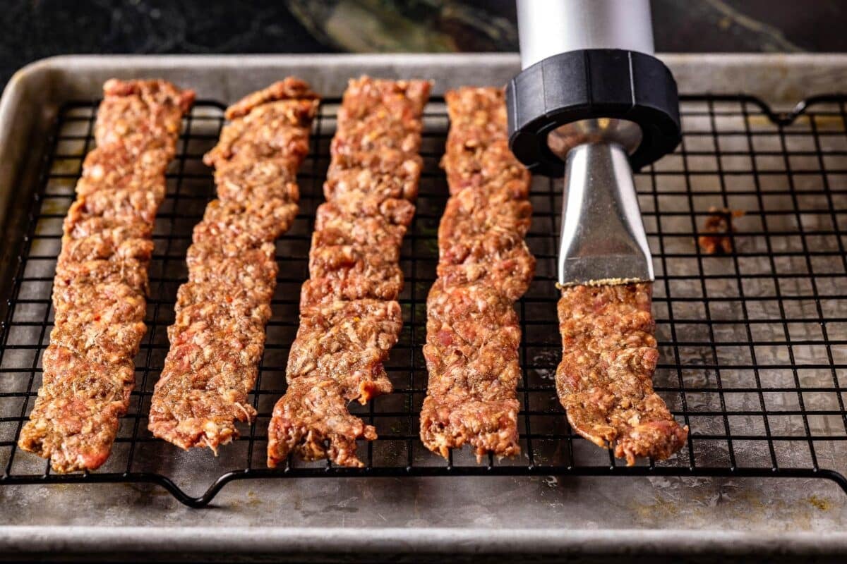 A jerky cannon laying out strips on a wire rack.