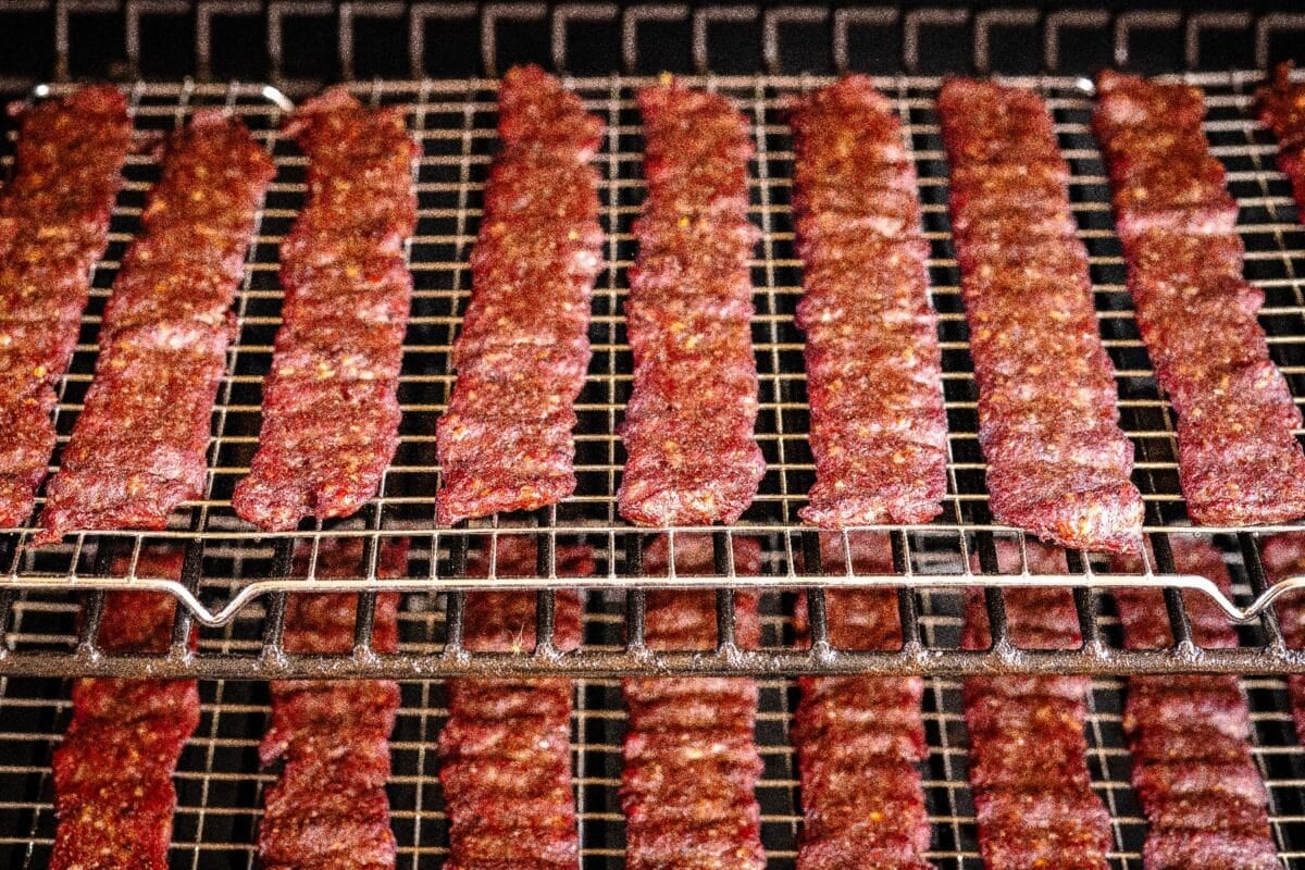 Strips of jerky drying on smoker racks.