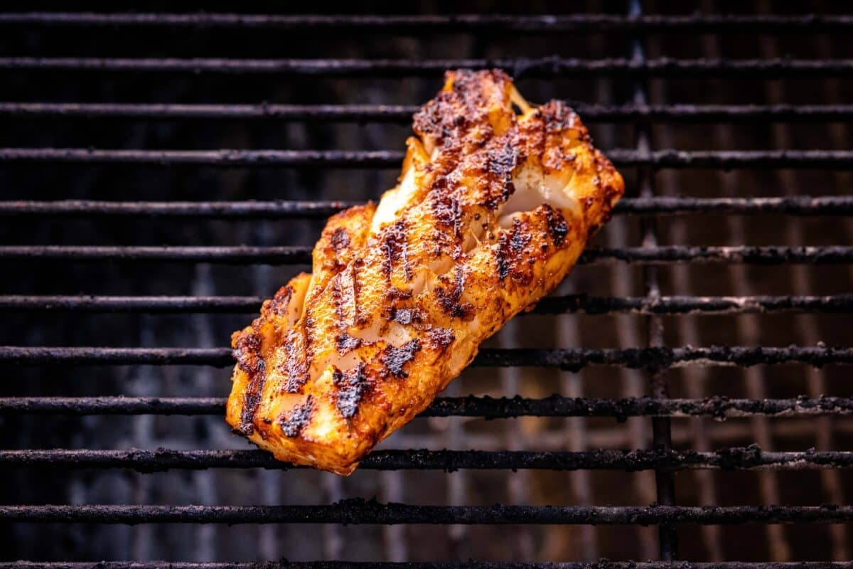 A Mahi Mahi fillet on the grill with grill marks on top of it.