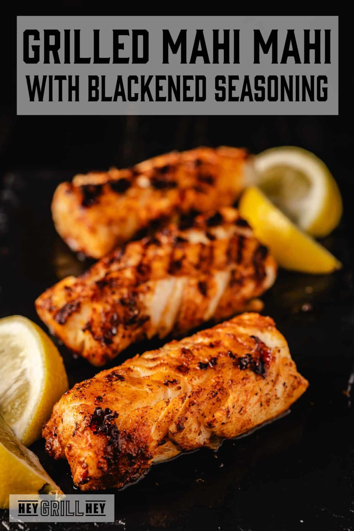 Grilled fish fillets and lemon wedges on a black surface. The text overlay reads "Grilled Mahi Mahi with Blackened Seasoning" at the top, and "Hey Grill Hey" at the bottom.