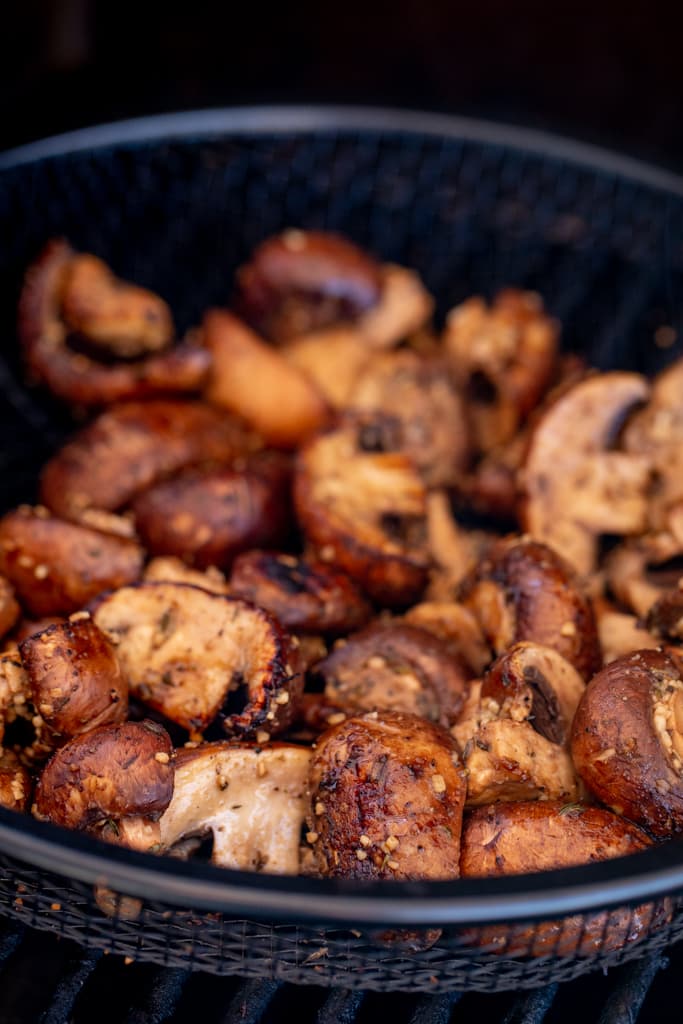 Marinated and grilled mushrooms in a metal grill basket.