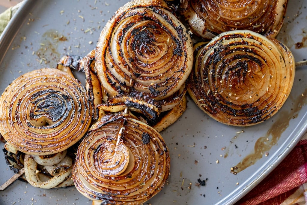 Grilled onion slices on a metal baking dish.