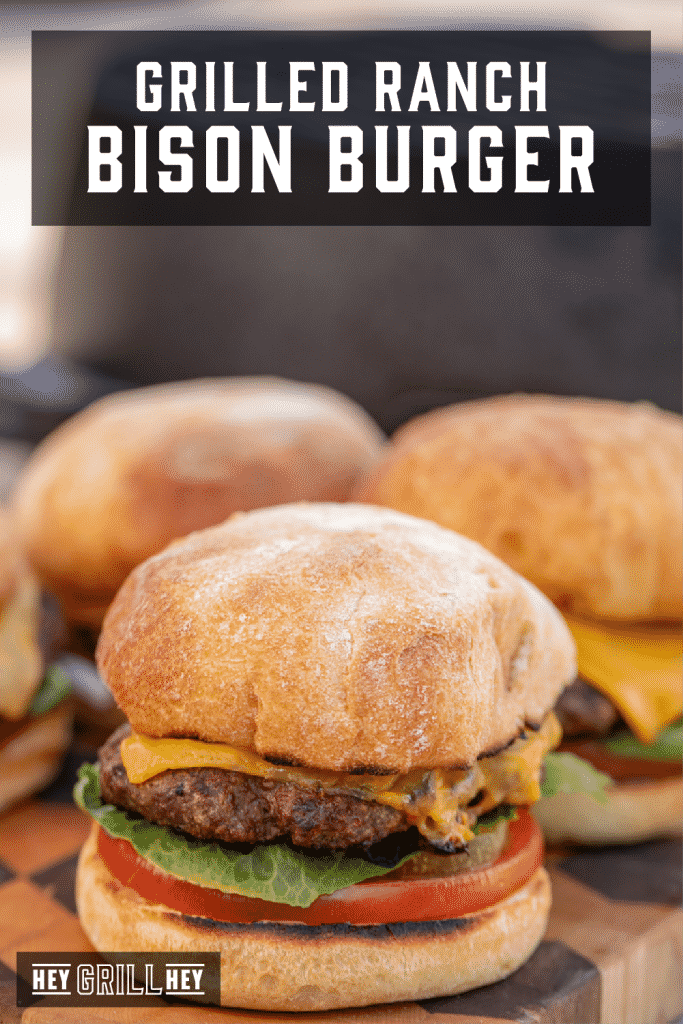 Grilled ranch bison burgers on a wooden cutting board with text overlay - Grilled Ranch Bison Burger.