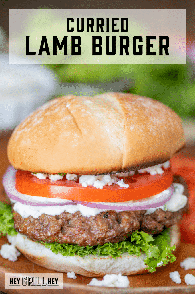 Lamb Burger topped with tomato, onion, lettuce, and feta cheese with text overlay - Grilled Lamb Burger.