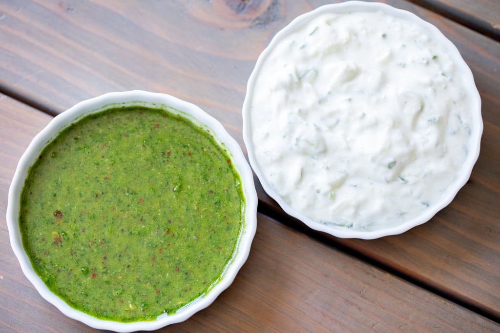 Mint sauce and tzatziki sauce in white bowls.
