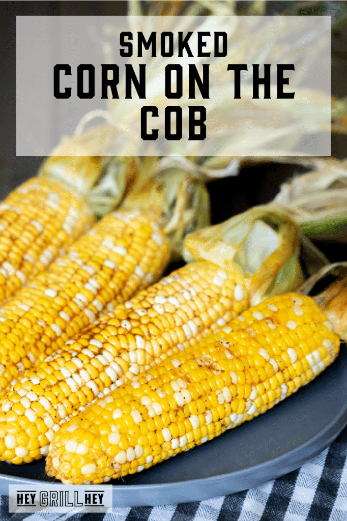 Four ears of smoked corn on the cob on a gray plate with text overlay - Smoked Corn on the Cob.