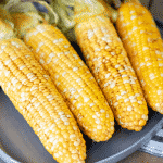 Four ears of smoked corn on the cob on a gray plate.