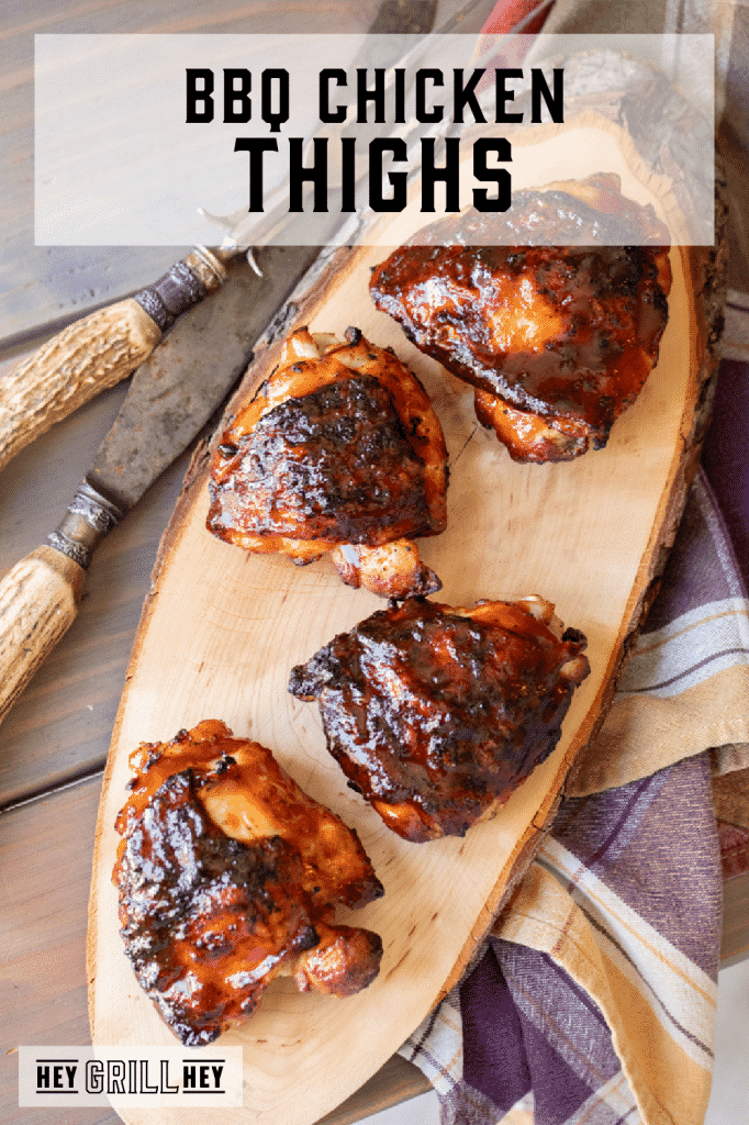 Four BBQ chicken thighs on a long, wooden cutting board with text overlay - BBQ Chicken Thighs.