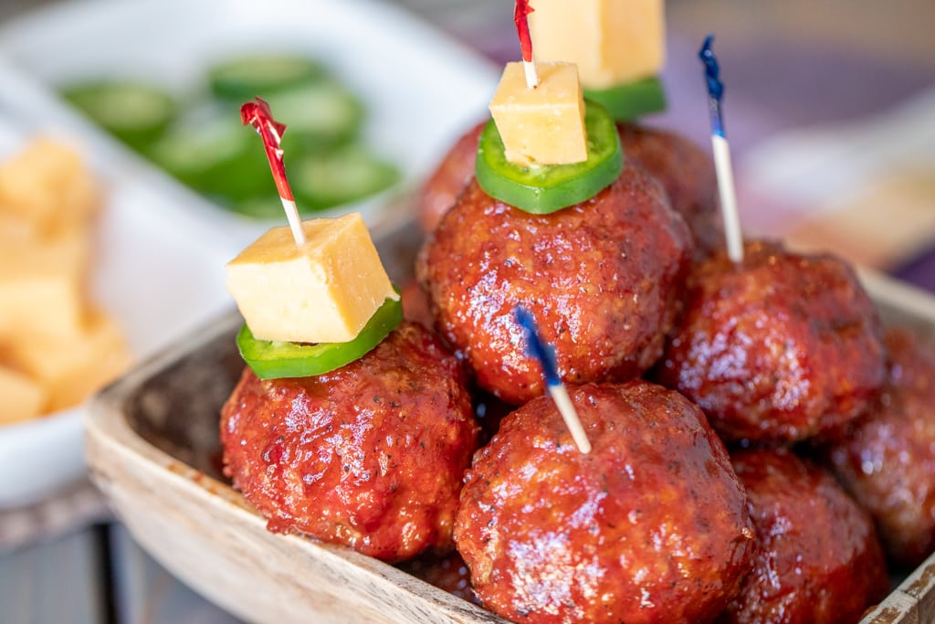 BBQ meatballs garnished with cheese and jalapeno toothpicks.