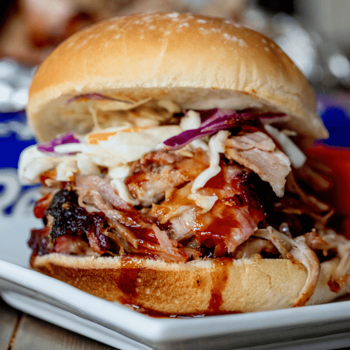 a pulled pork sandwich on a white plate.
