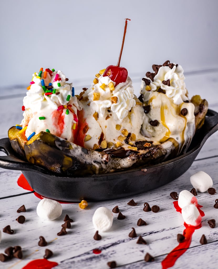 Grilled bananas topped with ice cream, sprinkles, and a cherry.