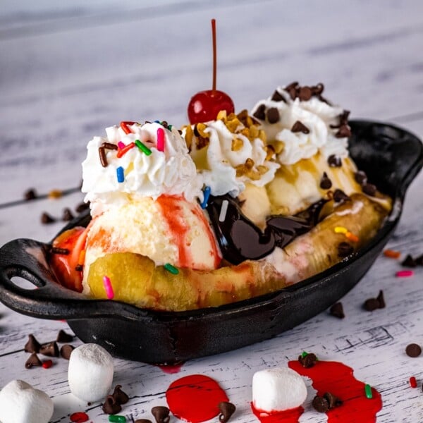 Grilled bananas topped with ice cream, sprinkles, and a cherry.