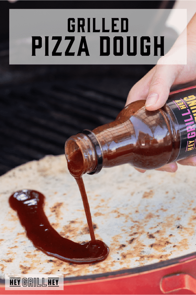 Pizza dough on a gas grill being drizzled with BBQ sauce with text overlay - Grilled Pizza Dough.