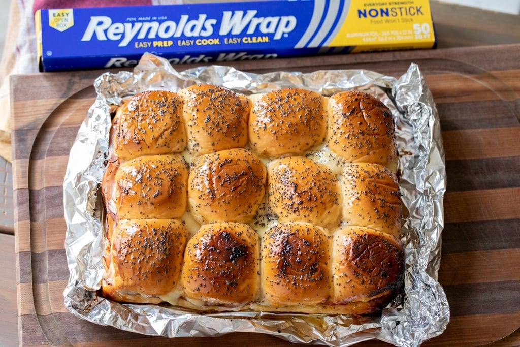 Grilled ham and cheese sliders in aluminum foil.