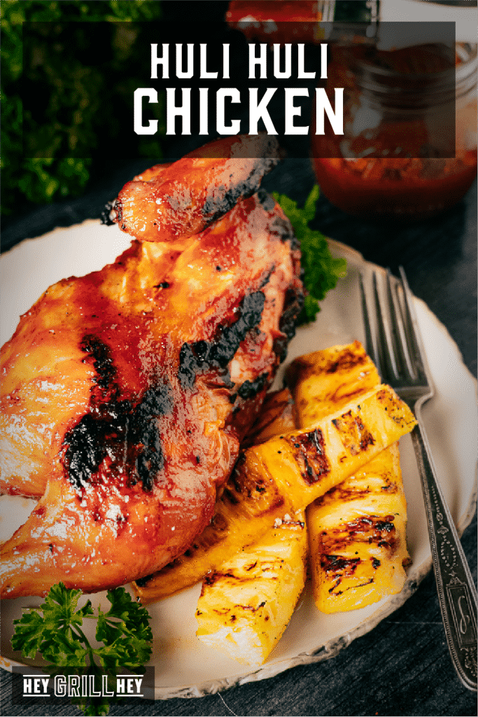Huli huli chicken on a white plate next to grilled pineapple spears with text overlay - Huli Huli Chicken.