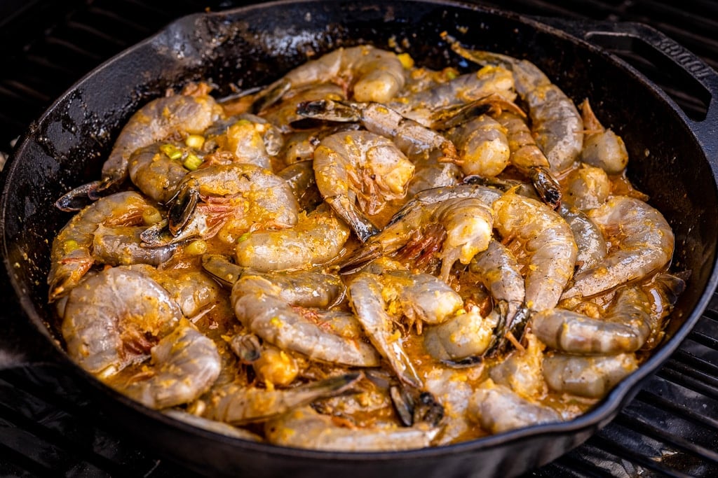 Cast iron skillet filled with seasoning-coated shrimp.