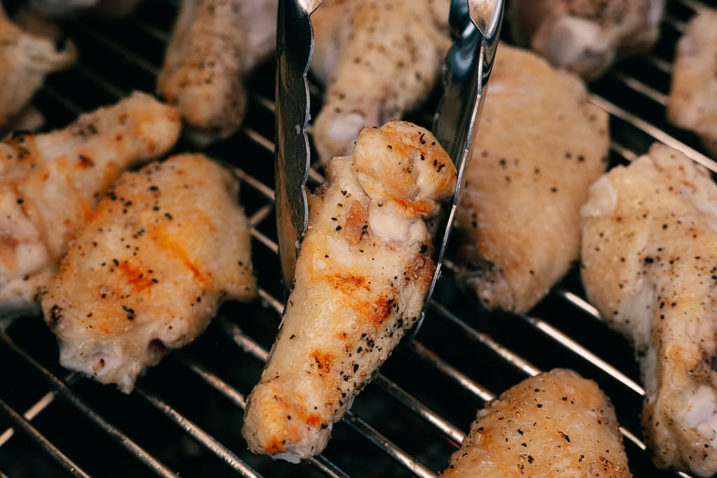 Seasoned chicken wings on a grill.