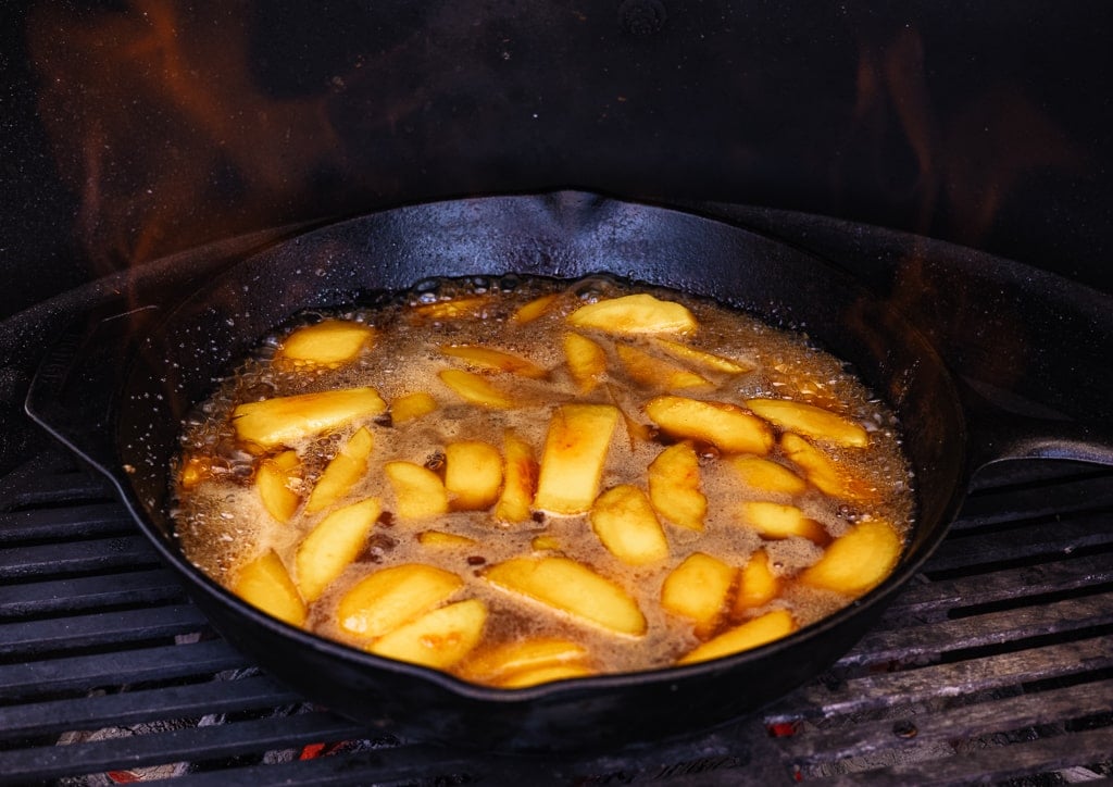 Peaches, water, and sugar in a cast iron skillet on the grill.