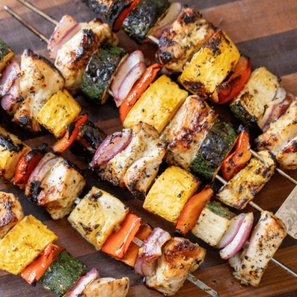 Grilled chicken and vegetable skewers on a wooden board.
